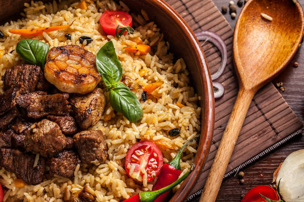乌兹别克餐厅概念, 乌兹别克美食盛宴。乌兹别克抓饭由牛肉, 羊肉, 鸡肉, 在大陶器, 盘子, 旁边的蔬菜。复制空间