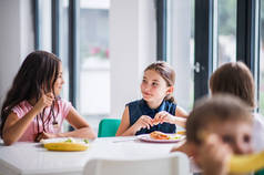 一群开朗的小学校孩子在食堂，吃午餐.