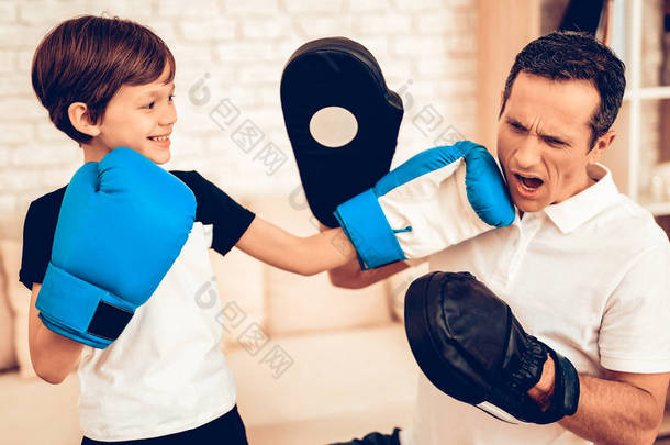 男孩站着。<strong>父子</strong>拳击手。在家运动。在季度热身。手里装拳击用品。拳击手套做运动。男人和男孩在家里训练。孩子在拳击手套在公寓。小男孩