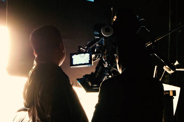 模糊图像的剪影人电影船员团队工作幕后拍摄视频制作与专业设备相机和照明<strong>工作室</strong>.