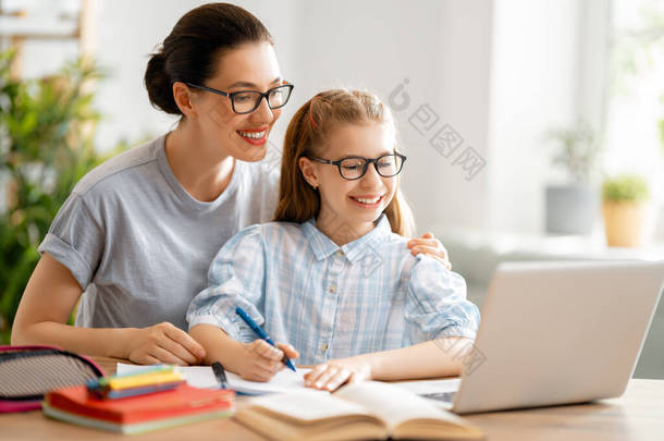 回学校去快乐的孩子和<strong>成年人</strong>正坐在办公桌前.做家庭作业或网上教育的女孩.
