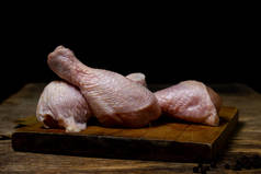 把鸡腿放在木板上.鸡腿的黑色背景。鸡肉.
