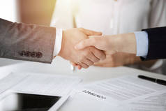 商务人员握手，在阳光明媚的办公室签合同，特写镜头。握手和营销