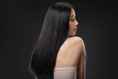 背面美丽的亚洲妇女与直和闪亮的头发孤立黑色
