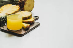 白底木制切菜板上的玻璃中新鲜菠萝汁近切美味水果的选择重点