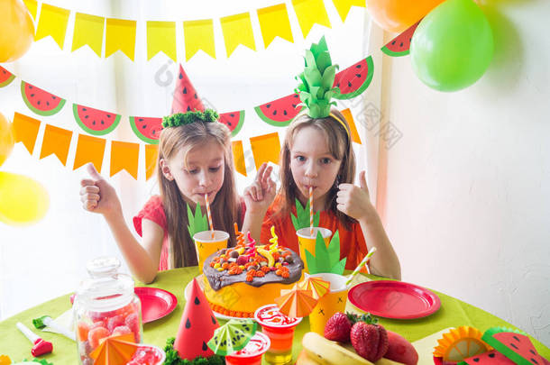 两个女孩庆祝他们的生日。水果派对。菠萝和西瓜服装。儿童假期.