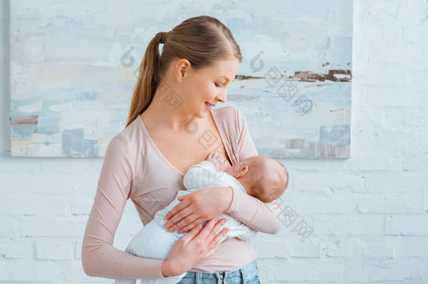 美丽的微笑的年轻母亲母乳<strong>喂养</strong>婴儿在家  