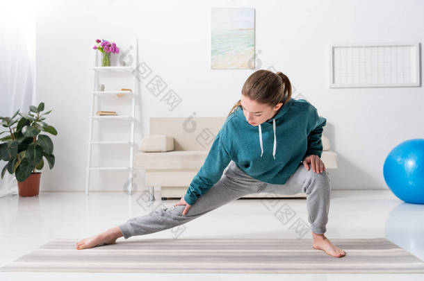 女孩舒展腿在瑜伽垫在家