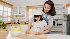 早上，带着学龄前孩子快乐地微笑着的年轻的亚洲日本家庭，在现代厨房的家里，吃着烤糕点或派当早餐。做糕点、揉搓面团和烘焙饼干.