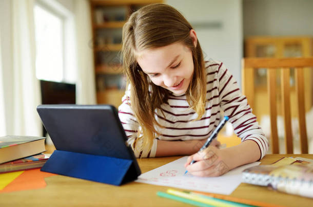 小学生在家里用数码平板电脑做作业。孩子们用小玩意来学习。儿童的教育和远距离学习。检疫期间在家学习。待在家里娱乐.