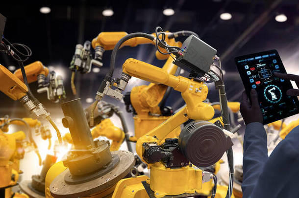 工厂的女工业工程师在智能化工厂的自动化机械臂机器上进行实时监测系统软件的工作。数字未来制造.