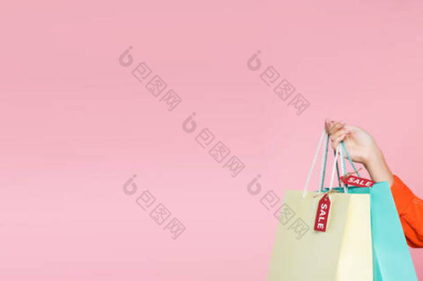 全景照片：一个惊讶的女人拿着标有价签的购物袋，用<strong>粉色背景</strong>的智能手机聊天