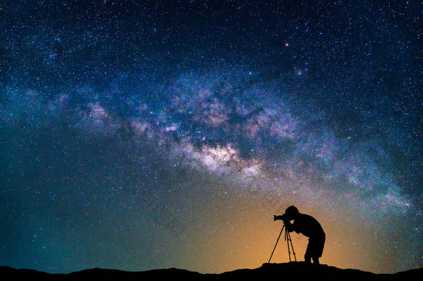 景观与银河系。夜空的星星与摄影师拍照在山上.
