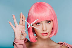 有吸引力的时尚女孩在粉红色的假发摆姿势剪刀剪刀孤立在蓝色