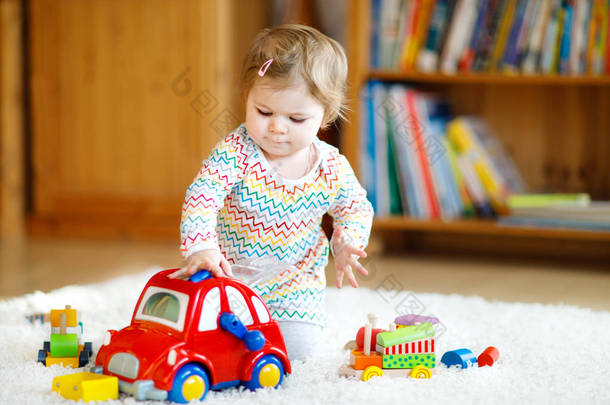 可爱可爱的小女孩玩的教育木制玩具在家或托儿所。带五颜六色<strong>红色汽车</strong>的小孩