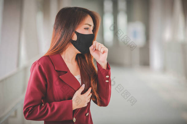 亚洲女人戴着口罩来保护pm2.5，并在公众场合咳嗽Covid-19病毒的爆发，但她患有严重的咳嗽和胸痛.