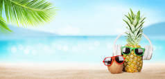夏日的热带海，波光灿烂，菠萝，太阳镜和耳机在炎热的沙滩上。带有复制空间的旅行和休假概念