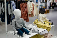 在一家儿童服装商店的橱窗里，坐着的白色婴儿模特儿没有脸。儿童服装商店.有选择的重点.