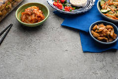 碗中的泡菜和混凝土表面筷子旁边的蓝色布罐子 