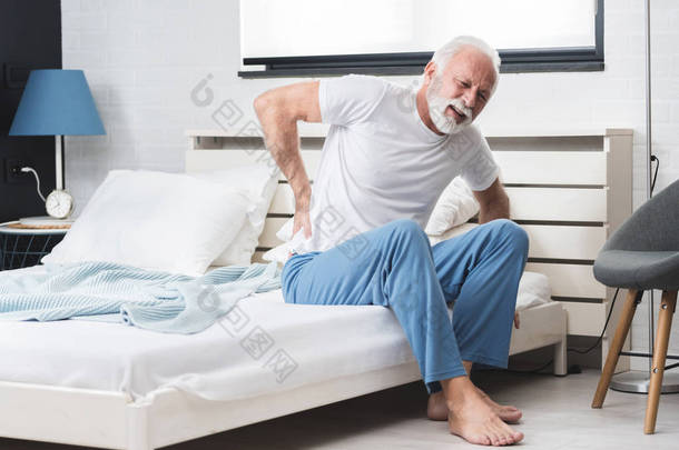 只有白发大胡子的老人一个人坐在床上，腰痛难忍