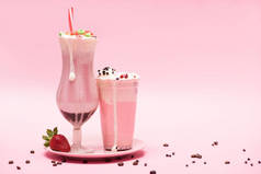 可处置的杯子和杯子，盘中放草莓，粉红背景的咖啡粒