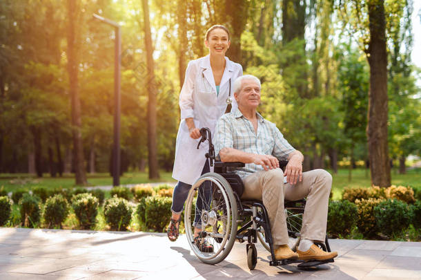 医生与老人坐轮椅在阳光公园散步