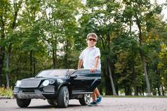 可爱的男孩在公园里骑一辆黑色电动车.有趣的男孩骑在玩具电动车上.一个快乐的小男孩开着一辆黑色的电动车在公园里。复制空间.