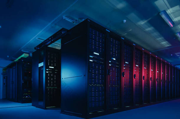 具有多行完全可操作的服务器机架的数据中心拍摄。现代电信,云计算,人工智能,数据库,超级计算机技术概念。拍摄在黑暗中与霓虹灯蓝色,粉红色光.