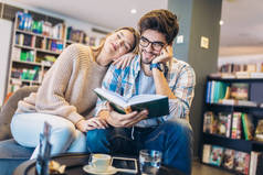 有吸引力的年轻夫妇一起读书在图书馆里 