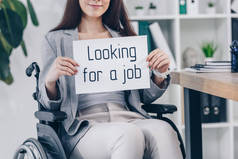 看到残疾员工拿着标语牌笑着寻找工作时，坐在轮椅上的样子
