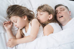 孩子们，女儿们，爸爸在床上睡在毛毯下的枕头上爸爸打呼噜很厉害。家人合睡。睡眠不足，该睡觉了，做个好梦。醒来，升入幼儿园，上学，工作.
