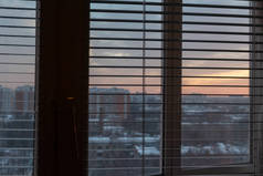 窗口与百叶窗剪影在早晨或晚上黄昏, 都市土地 cape 在背景.