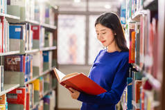 亚洲青年学生身着休闲服，在大学图书馆的书架上看书，或以各种书本背景，回到学校概念