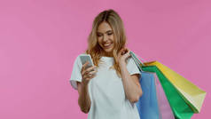 快乐的女人用智能手机，提着用紫色隔开的购物袋