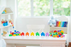儿童卧室配有白色书桌和教育玩具块。五颜六色的方块玩具为幼儿。托儿所或日托所。男孩或女孩的幼儿园或学前班.