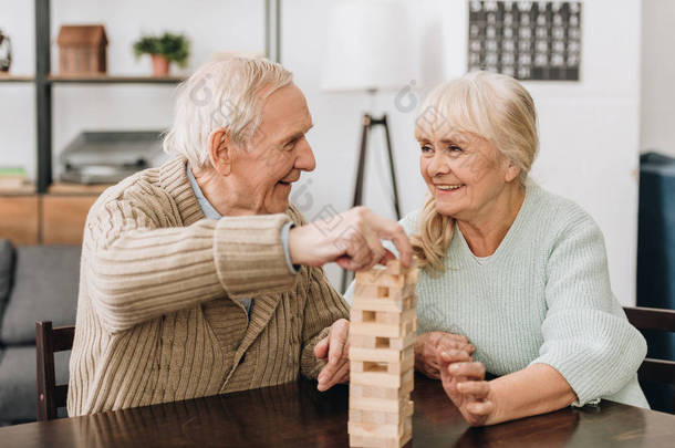 微笑的退休人员玩 jenga 游戏在桌子上