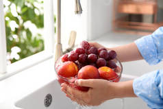 妇女在厨房洗碗槽里洗新鲜葡萄和油桃，特写镜头