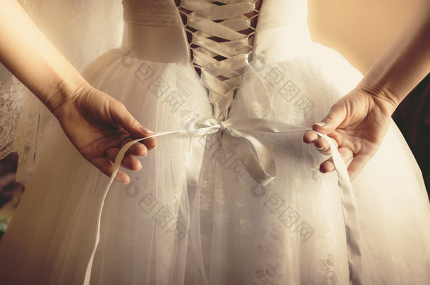 定了调子的美丽的新娘捆绑她的婚纱照片