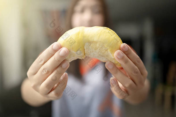 女人拿着一个美味的黄色榴莲，榴莲肉吃。榴莲是泰国的水果之王.