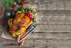 传统的圣诞和感恩节烤整只鸡与水果和迷迭香。简朴的木制圣诞餐桌，配有圣诞树枝条和装饰品复制空间
