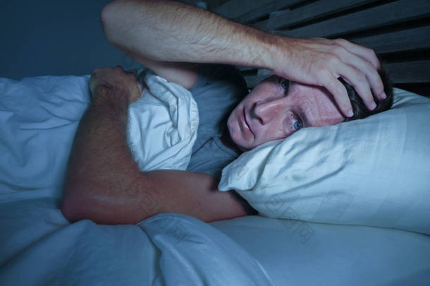 焦躁不安的年轻有吸引力的男人睡在床上睡不着, 睁大眼睛睡不着觉失眠睡眠障碍抑郁和悲伤的休息贫困压力概念