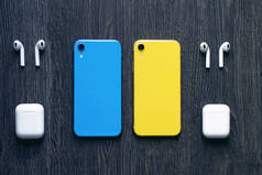 两个彩色手机和无线蓝牙耳机。蓝色和黄色电话 