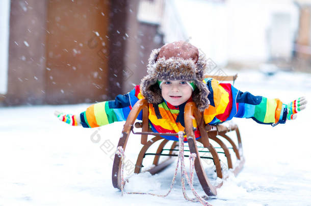 小男孩喜欢在<strong>降雪</strong>时乘坐雪橇。坐着老式雪橇的学龄前儿童快乐.