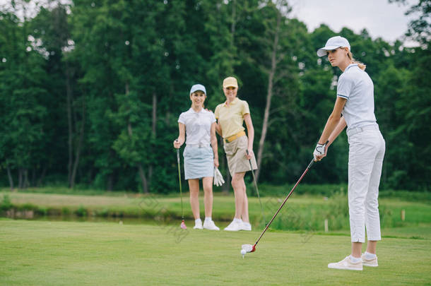 在高尔夫球场附近的朋友站在高尔夫球场上打高尔夫的妇女选择焦点