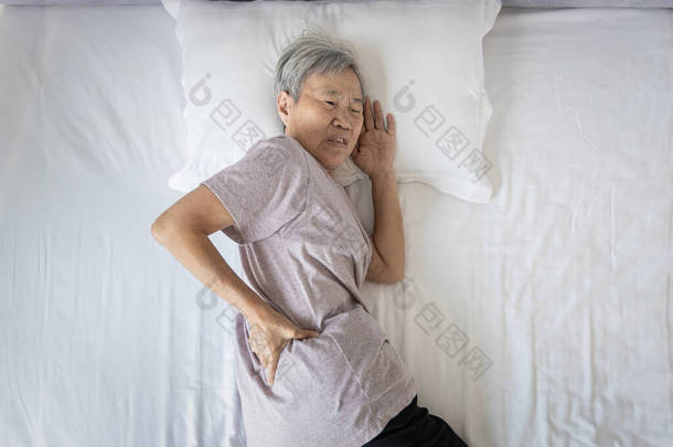 亚洲老年妇女背痛，睡觉时腰酸背痛，不快乐的老年妇女在床上休息时由于姿势不好或床垫不<strong>舒服</strong>而感到背部肌肉不<strong>舒服</strong>