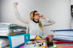 昏昏欲睡的商界女强人做她工作坐在办公桌前全关打哈欠厌倦或累熬夜的粘合剂中的文档工作.