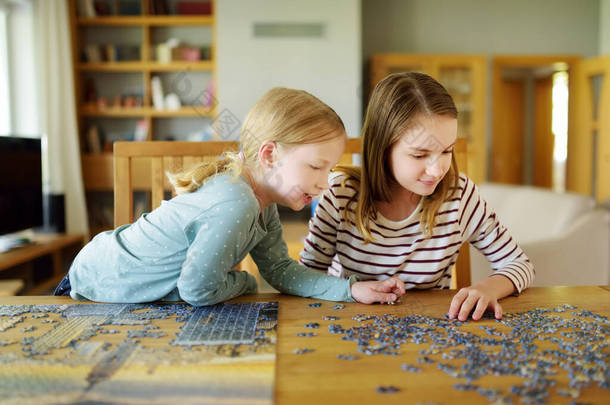 可爱的小女孩在家里玩拼图游戏。孩子们在客厅的桌子上把拼图拼图连在一起.孩子们在拼凑拼图快乐的家庭休闲。为孩子们在家里活动.