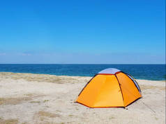 在大海和天空背景的沙上橙色帐篷
