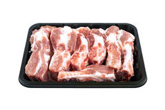 在白色背景的黑色托盘容器中分离有机备用肋骨。猪肉备用排骨的软部分.新鲜的生排骨排成小盘出售.