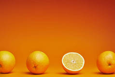 新鲜成熟的整体特写镜头视图和橙色背景上的一半橙子 
